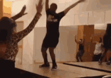 a group of people are dancing in a room with a man wearing a shirt that says life