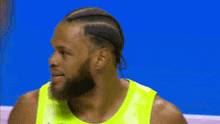 a man with a beard wearing a bright yellow shirt is smiling