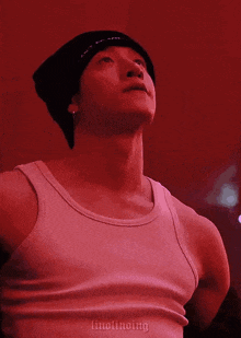 a man wearing a tank top and a beanie is looking up at the sky .