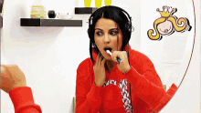 a woman wearing headphones is brushing her teeth in front of a round mirror