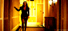 a woman in a black dress is walking down a hallway with anitaztumblr written on the bottom right
