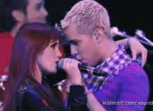 a man singing into a microphone next to a woman with walmart.com in the corner