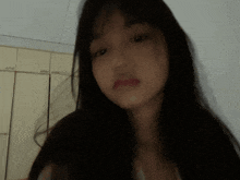 a woman with long black hair looks at the camera with a serious look on her face