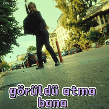 a man walking down a street with the words " goruldu atma bana " written below him