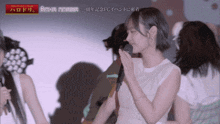 a woman in a white dress holds a microphone in front of a sign that says bighit morina