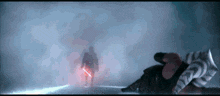 a man holding a red lightsaber is standing in the dark
