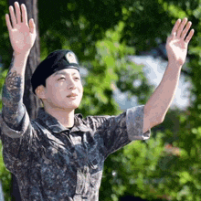 a young man in a military uniform is waving his hand