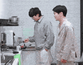 two men are standing in a kitchen and one of them has the word naughty written on the bottom