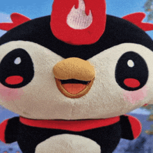 a close up of a stuffed animal with a red flame on its head