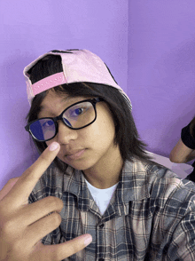 a person wearing glasses and a pink hat is making a peace sign
