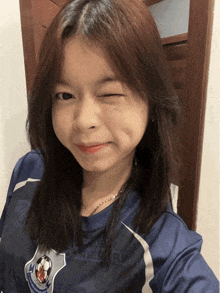 a girl wearing a blue shirt with a soccer ball on it winks at the camera
