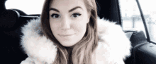 a woman in a white fur coat is sitting in the back seat of a car