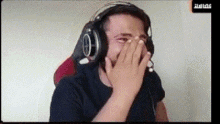 a man wearing headphones is covering his face .