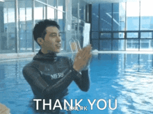 a man in a wet suit is clapping in a swimming pool and the words thank you are below him .