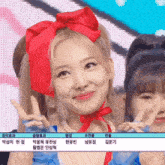 a girl with a red bow in her hair is smiling and giving a peace sign