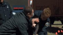 a man in a suit and tie is being held by a police officer with a nyc patch on his jacket