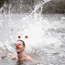 a man wearing a clown nose is swimming in a river