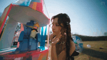 a woman is standing in front of a colorful building with a stuffed animal inside of it