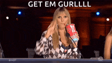 a woman is sitting in front of a microphone holding a cup of soda and drinking it .