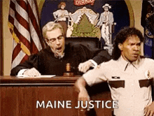 a man in a sheriff 's uniform is sitting in front of a judge in a court room .