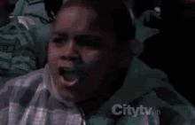 a boy is making a funny face while sitting in a crowd of people .