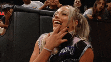 a woman is laughing while sitting in a crowd with a man wearing a baseball cap with the letter b on it